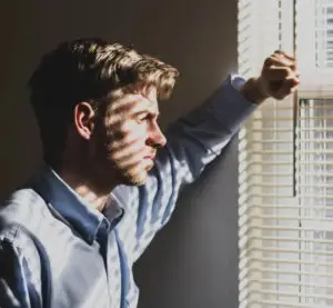 Symbolbild zum Coaching bei vermeidendem Bindungsstil. Eine nachdenkliche Person schaut aus dem Fenster.