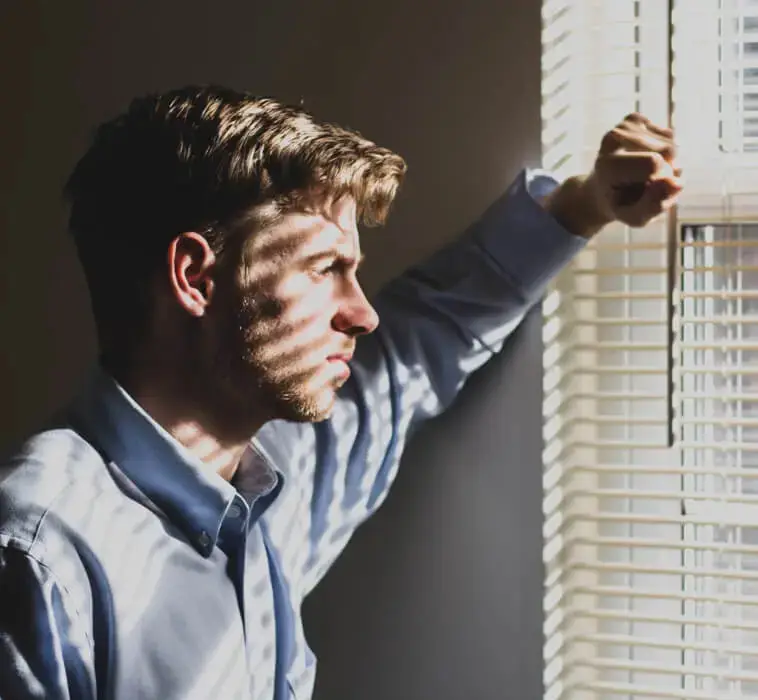 Symbolbild zum Coaching bei vermeidendem Bindungsstil. Eine nachdenkliche Person schaut aus dem Fenster.